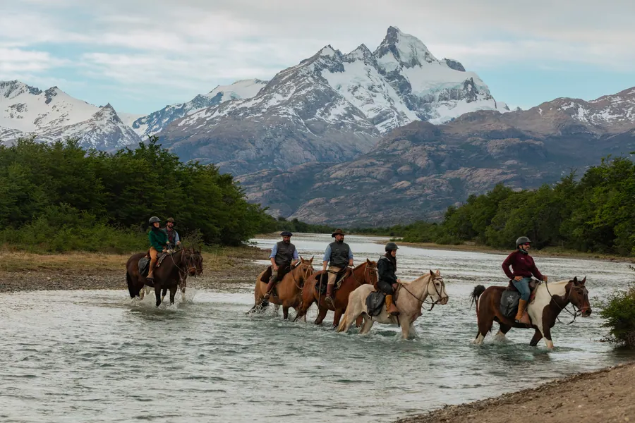 Cabalgata cruzando el río en el paisaje de Estancia Cristina