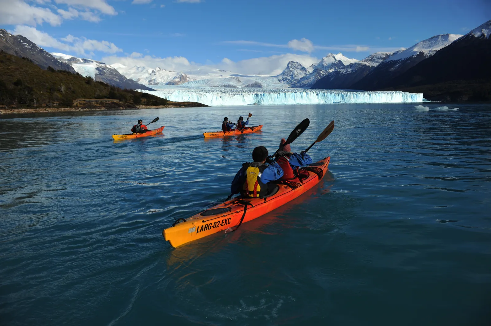 Kayaks navegando frente al Glaciar Perito Moreno y las montañas patagónicas