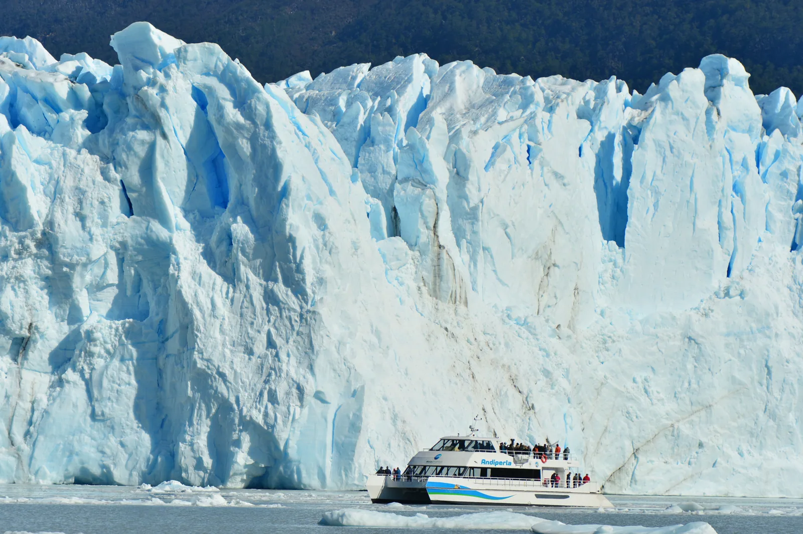 Embarcación navegando frente a la pared de hielo del glaciar Perito Moreno