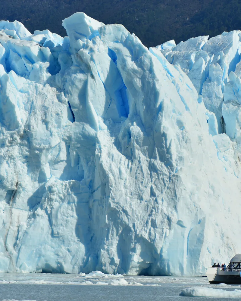 Embarcación navegando frente a la pared de hielo del glaciar Perito Moreno